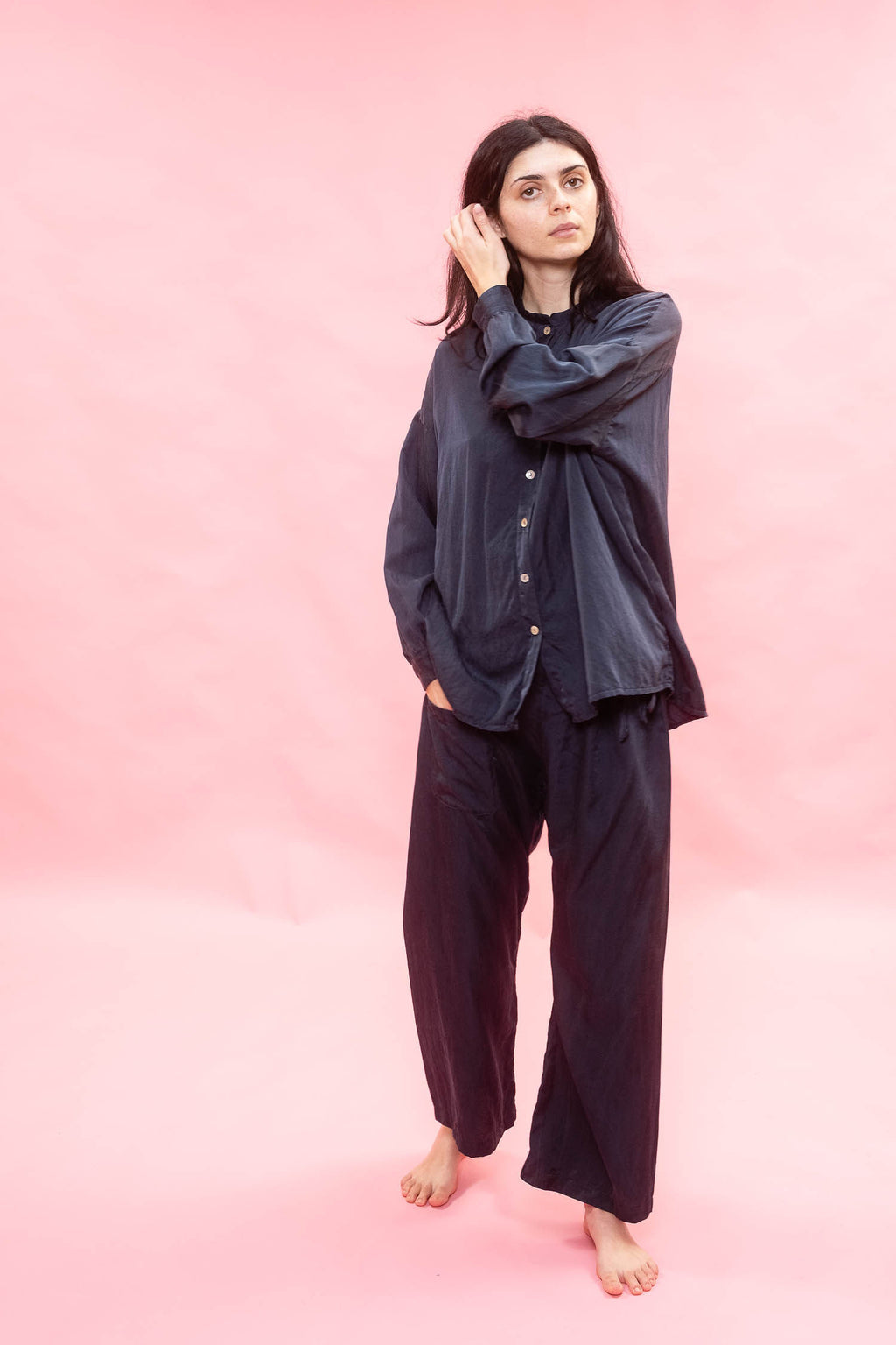 Woman wearing a dark blue silk cotton satin shirt on a pink background
