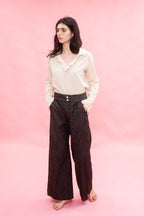 Woman wearing a cream cotton japanese Organdy blouse and dark pants on a pink background
