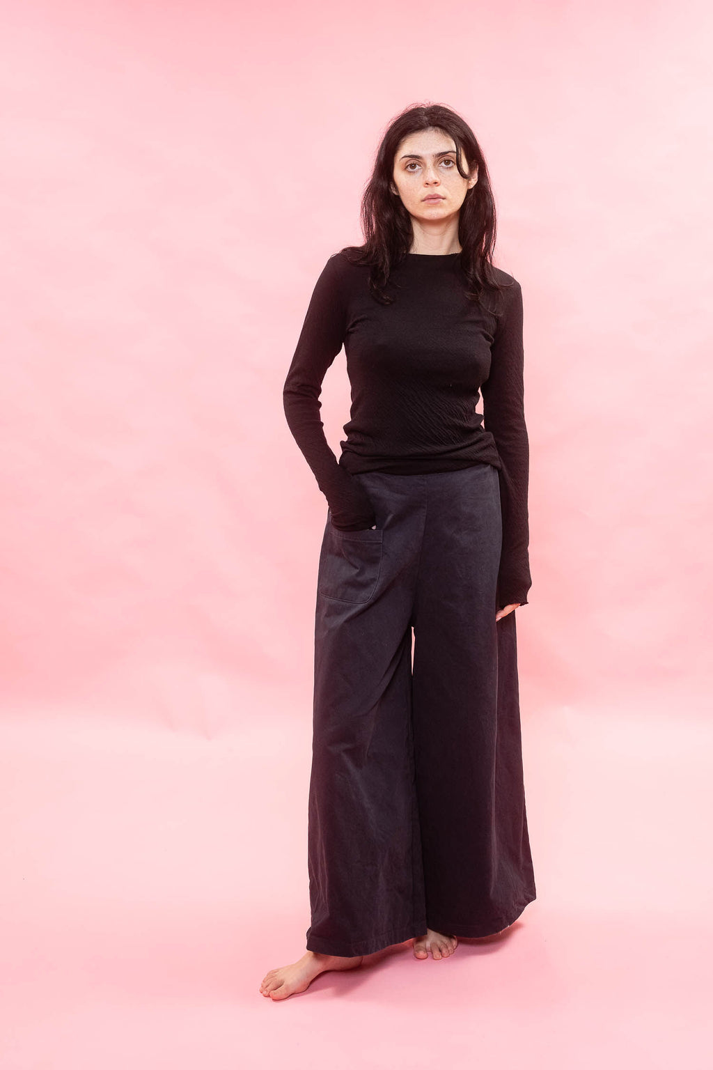 Person wearing a black long sleeve tee, cut from Japanese cotton double jersey on a pink background
